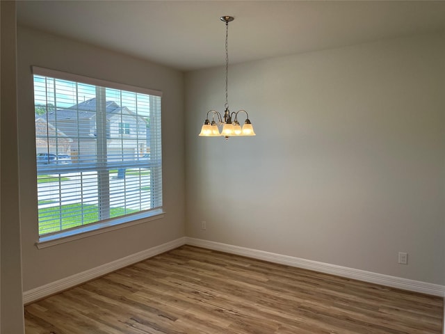 unfurnished room featuring a notable chandelier, wood-type flooring, and a wealth of natural light