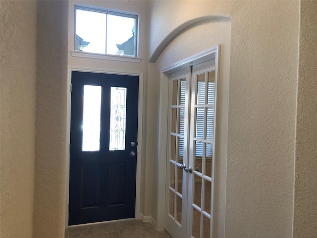 foyer entrance with a wealth of natural light, tile patterned flooring, and french doors