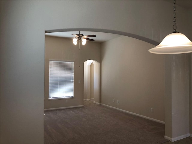 spare room with ceiling fan and dark carpet