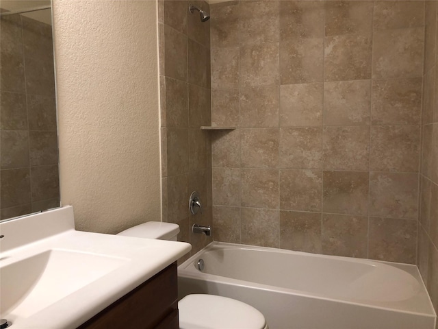 full bathroom with tiled shower / bath, vanity, and toilet