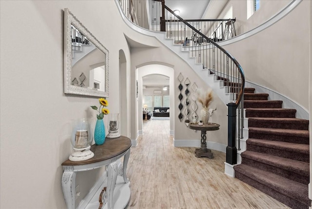 foyer with ceiling fan, light hardwood / wood-style floors, and a towering ceiling