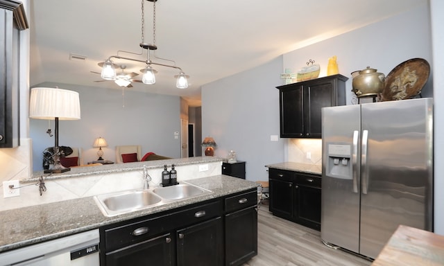 kitchen featuring dishwasher, sink, stainless steel fridge, pendant lighting, and light wood-type flooring