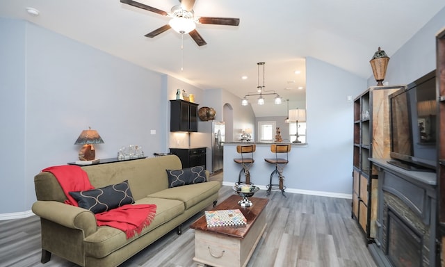 living room with a fireplace, wood-type flooring, vaulted ceiling, and ceiling fan