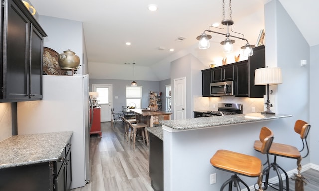 kitchen with backsplash, hanging light fixtures, stainless steel appliances, and lofted ceiling