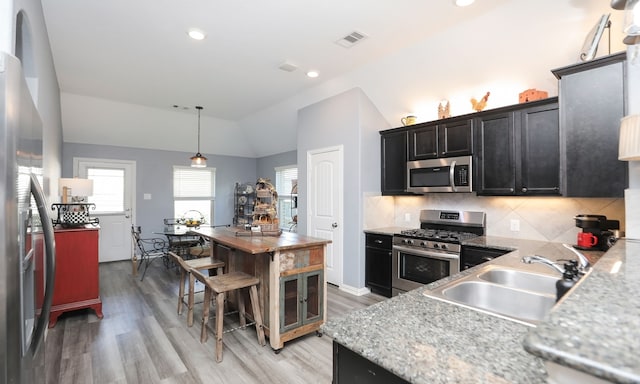 kitchen featuring lofted ceiling, hanging light fixtures, sink, appliances with stainless steel finishes, and tasteful backsplash