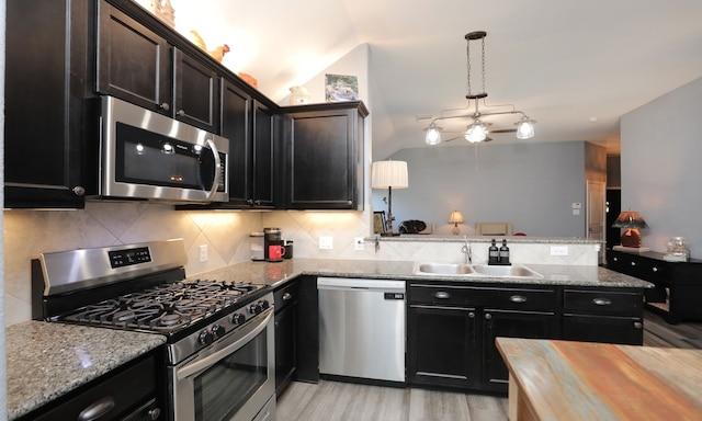 kitchen featuring sink, tasteful backsplash, decorative light fixtures, appliances with stainless steel finishes, and light wood-type flooring