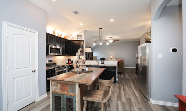 kitchen with pendant lighting, vaulted ceiling, ceiling fan, appliances with stainless steel finishes, and a kitchen island