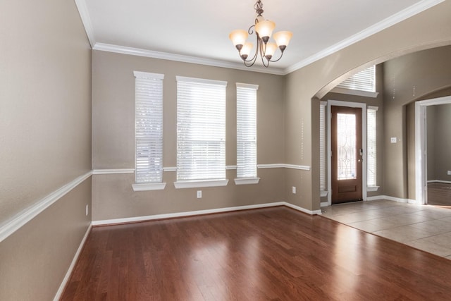 entryway with a wealth of natural light, dark hardwood / wood-style flooring, crown molding, and a notable chandelier