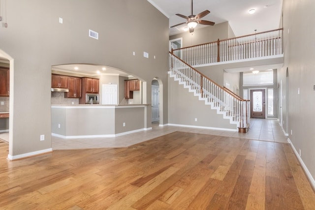 unfurnished living room featuring a high ceiling, light hardwood / wood-style floors, and ceiling fan