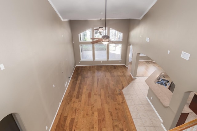 entryway with light tile patterned floors, ceiling fan, and ornamental molding