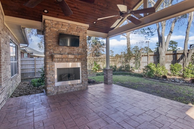 view of patio with an outdoor stone fireplace and ceiling fan