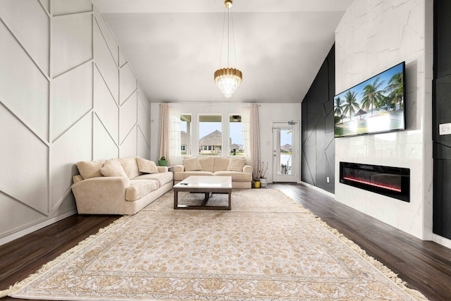 living room featuring dark wood-type flooring, an inviting chandelier, lofted ceiling, and a tiled fireplace