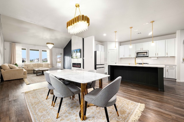 dining space with a fireplace, dark hardwood / wood-style flooring, lofted ceiling, and sink