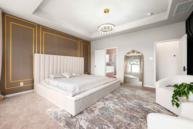 carpeted bedroom with a raised ceiling, connected bathroom, and a notable chandelier