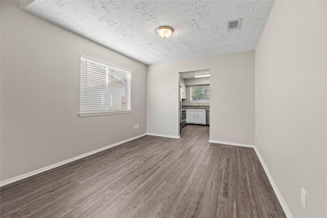 empty room featuring dark hardwood / wood-style flooring and a textured ceiling