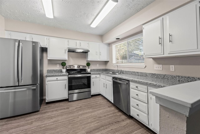 kitchen with sink, stainless steel appliances, light hardwood / wood-style floors, a textured ceiling, and white cabinets