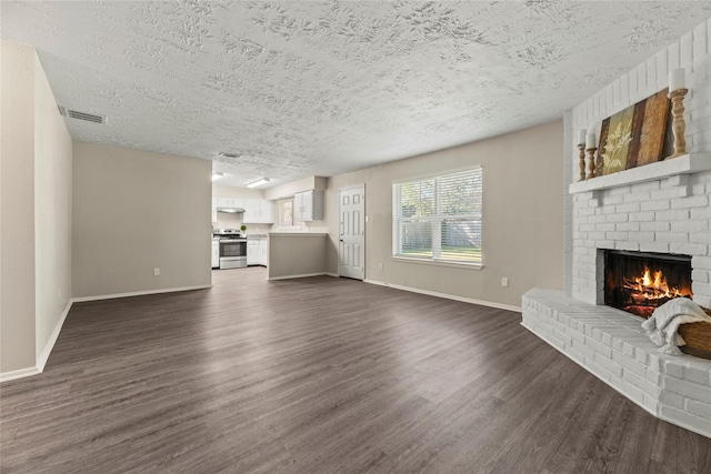 unfurnished living room featuring a fireplace, a textured ceiling, and dark hardwood / wood-style flooring