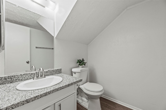 bathroom with a textured ceiling, toilet, vaulted ceiling, vanity, and hardwood / wood-style flooring