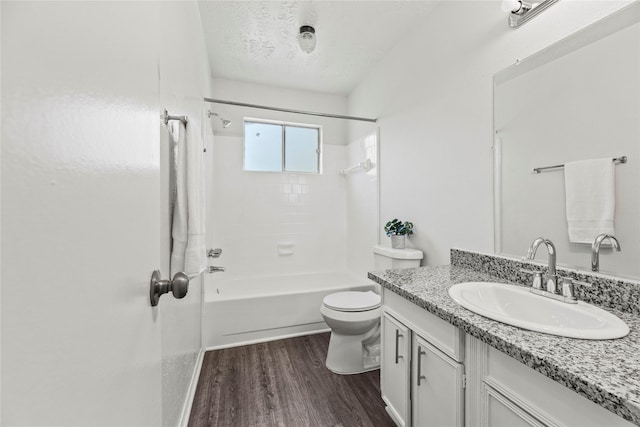 full bathroom featuring hardwood / wood-style floors, vanity, shower / tub combination, toilet, and a textured ceiling