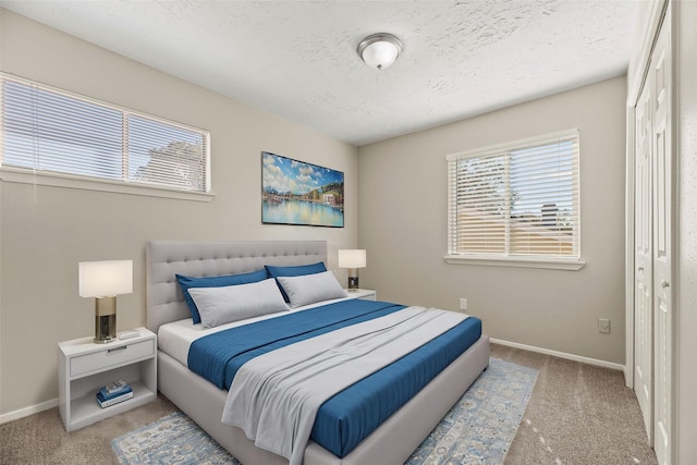 bedroom with light colored carpet, a textured ceiling, and a closet