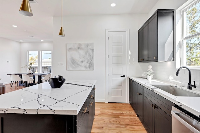 kitchen featuring sink, a center island, light stone counters, stainless steel dishwasher, and decorative backsplash