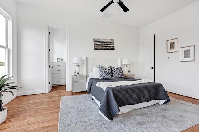 bedroom with light wood-type flooring, ensuite bathroom, and ceiling fan