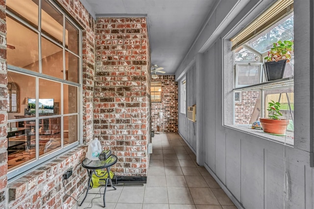 hall with light tile patterned flooring and brick wall