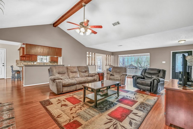 living room featuring vaulted ceiling with beams, ceiling fan, sink, and light wood-type flooring