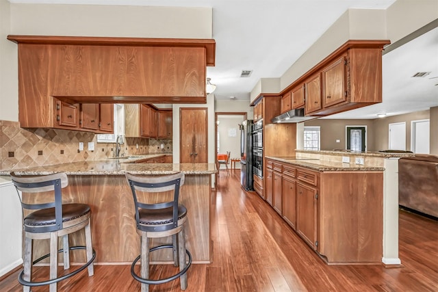 kitchen with sink, a kitchen bar, kitchen peninsula, and backsplash