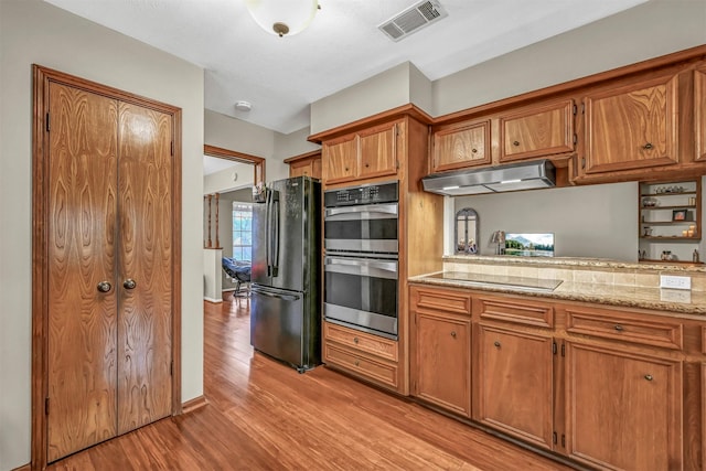 kitchen featuring black appliances, light stone countertops, and light hardwood / wood-style flooring