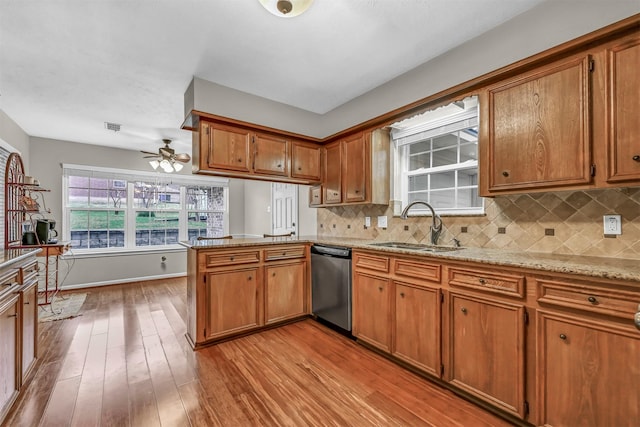 kitchen with sink, tasteful backsplash, stainless steel dishwasher, kitchen peninsula, and light hardwood / wood-style floors