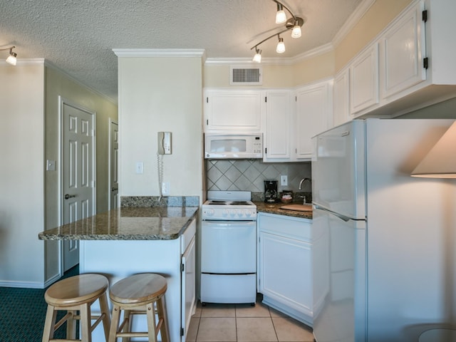 kitchen with white appliances, white cabinetry, and dark stone countertops