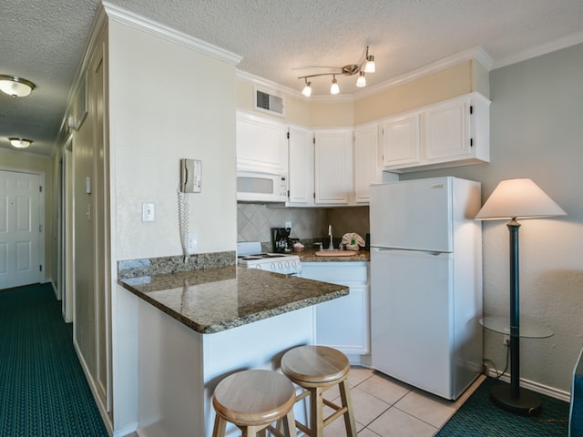 kitchen featuring kitchen peninsula, white appliances, light tile patterned floors, dark stone countertops, and white cabinetry