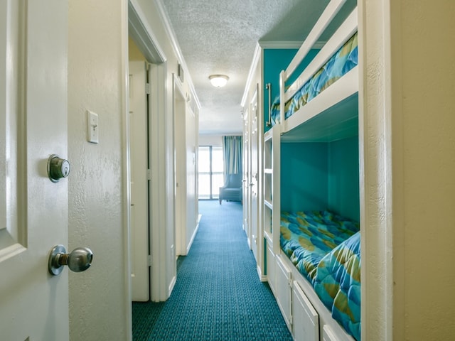 corridor with a textured ceiling, carpet floors, and ornamental molding