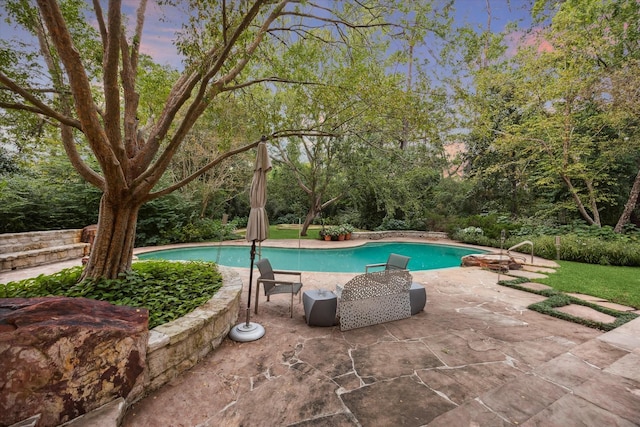 pool at dusk featuring a patio