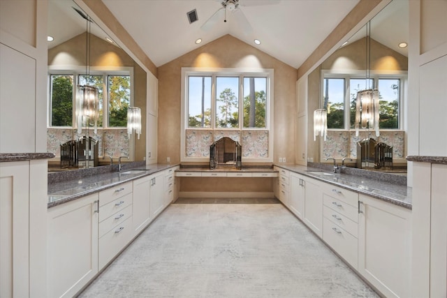 bathroom featuring a wealth of natural light, vanity, ceiling fan, and lofted ceiling