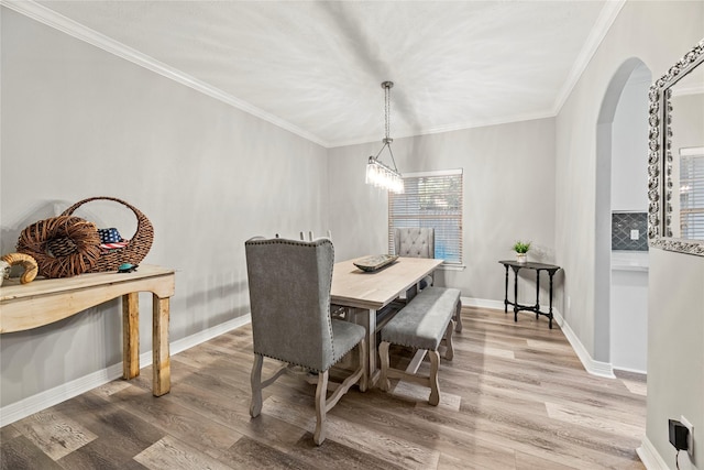 dining room with wood-type flooring, an inviting chandelier, and crown molding