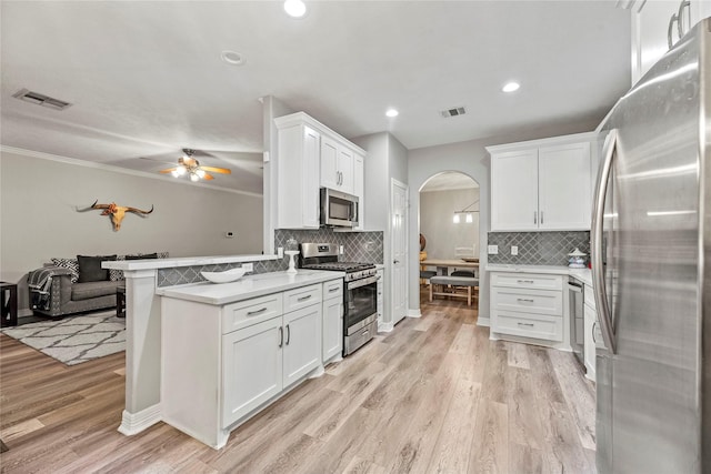 kitchen with kitchen peninsula, ceiling fan, white cabinetry, and stainless steel appliances