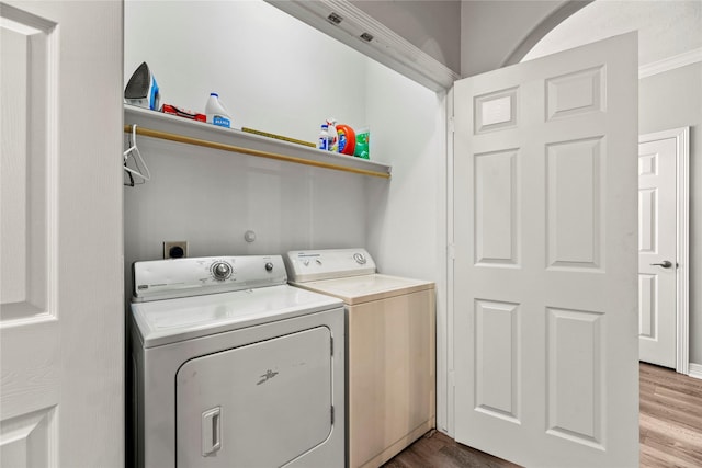 laundry room with separate washer and dryer, crown molding, and hardwood / wood-style flooring