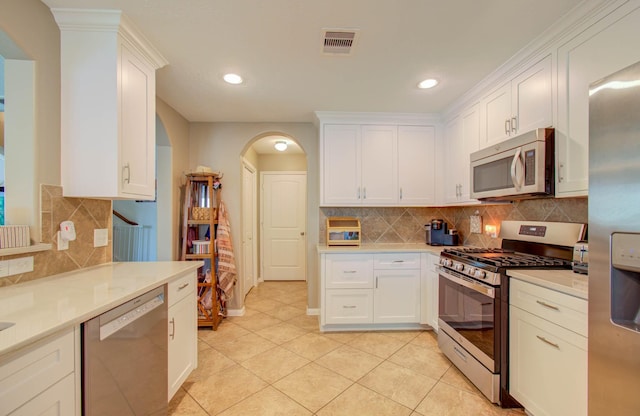 kitchen with white cabinets, appliances with stainless steel finishes, decorative backsplash, and light tile patterned floors