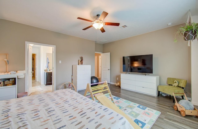 bedroom with ensuite bath, ceiling fan, and light hardwood / wood-style floors