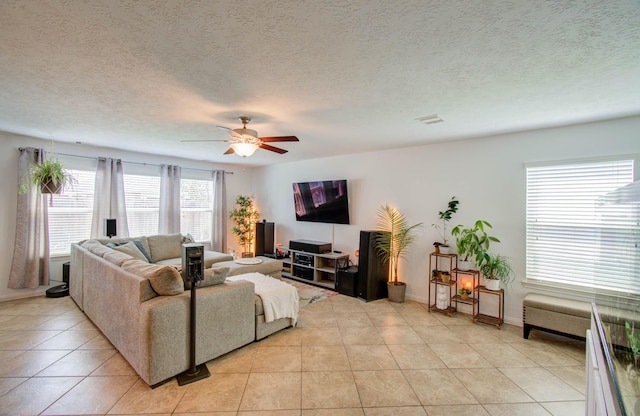 living room with ceiling fan, light tile patterned floors, and a textured ceiling