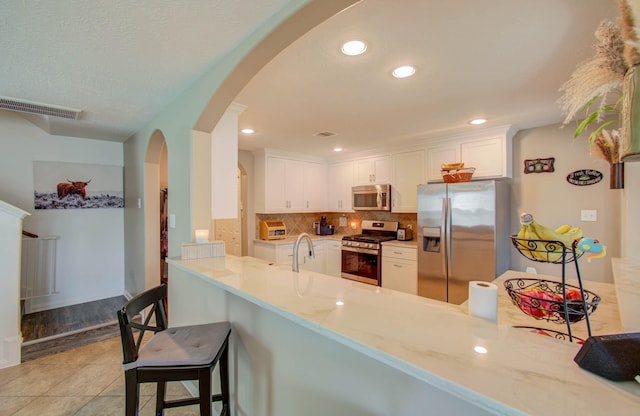 kitchen featuring white cabinetry, kitchen peninsula, stainless steel appliances, and a breakfast bar area