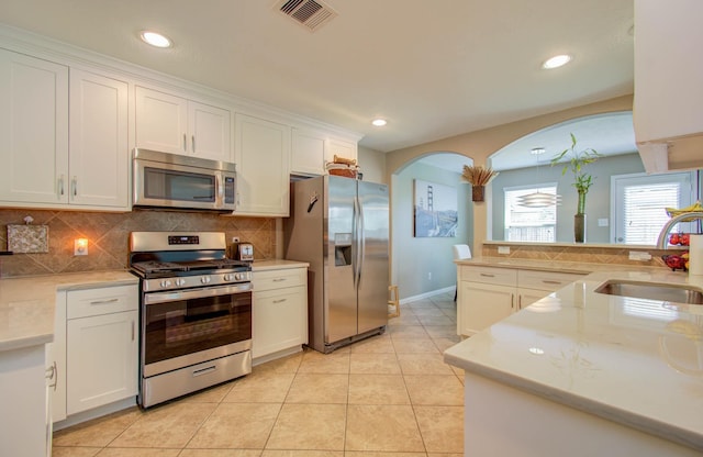 kitchen featuring white cabinets, backsplash, sink, and appliances with stainless steel finishes