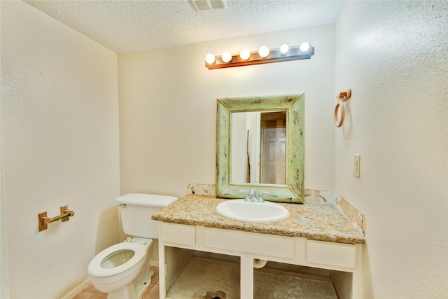 bathroom with vanity, a textured ceiling, and toilet