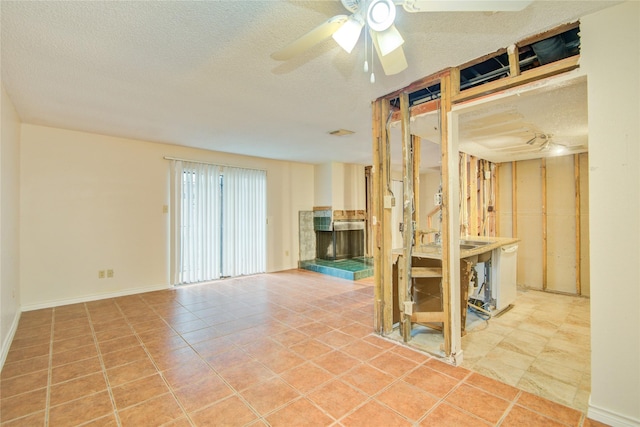 tiled spare room with a textured ceiling, ceiling fan, and a fireplace