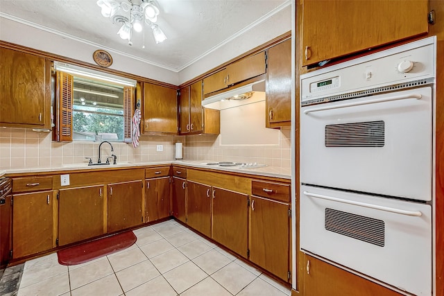 kitchen with double oven, tasteful backsplash, sink, light tile patterned floors, and crown molding