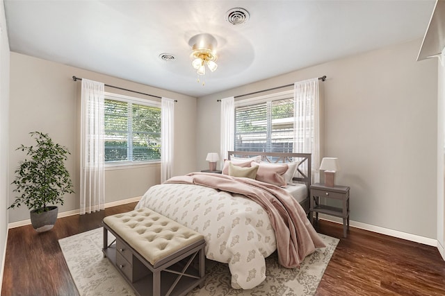 bedroom with dark wood-style floors, multiple windows, and visible vents