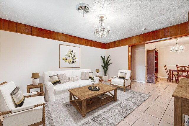 tiled living room featuring a notable chandelier and wood walls