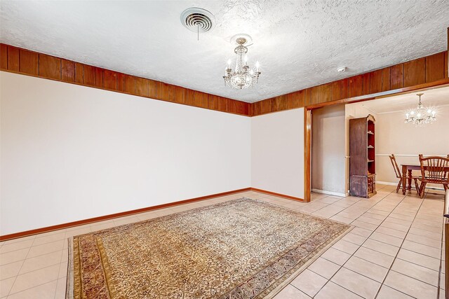 unfurnished room featuring a chandelier, light tile patterned floors, a textured ceiling, and visible vents